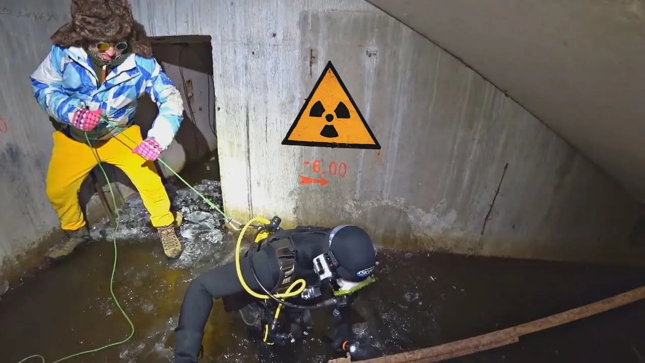 Two urbexers in a flooded concrete bunker, one in a wetsuit diving near a radiation sign.