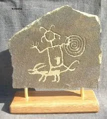 A petroglyph on a stone slab showing a horned figure and a centipede.